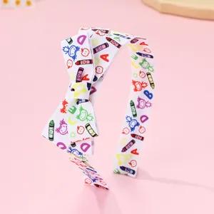 Detail of school-themed bow headband with colorful crayon graffiti on white ribbon