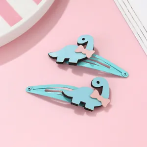Détail de barrettes dinosaure bleu clair avec nœuds roses pour enfants sur fond rose