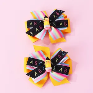Détail de barrettes scolaires avec rubans arc-en-ciel et petit crayon jaune décoratif