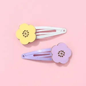 Detail of yellow and purple hollow flower hair clips with glitter centers on pink backdrop