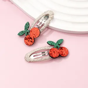 Detail of sweet cherry hair clips with red and green sequins on a pink display stand