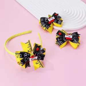 Detail of school-themed hair accessory set with yellow ruler ribbons and apple motifs