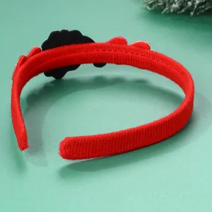 Dettaglio del cerchietto natalizio in tessuto rosso strutturato con decorazione floreale nera