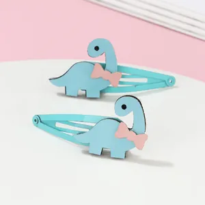 Gros plan de deux barrettes dinosaures bleu clair avec nœuds roses et texture cuir