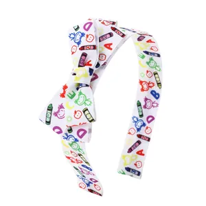 Detail of white grosgrain ribbon headband featuring colorful ABC crayon doodles and bows