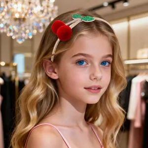 Cerchietto dorato glitterato con pompon a ciliegia rossa indossato da una bambina