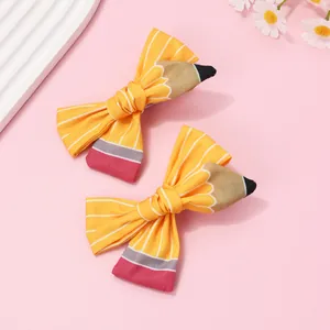 Détail de barrettes à nœuds motif crayon avec des rayures jaunes et blanches d'école