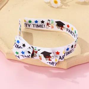 Detail view of white graduation headband with bow featuring festive printed diploma patterns