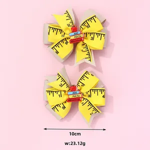 Close-up of school-themed bow clips with ruler print, apples, and miniature books