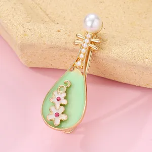 Elegant gold Pipa brooch featuring green enamel, plum blossoms, and pearl accents