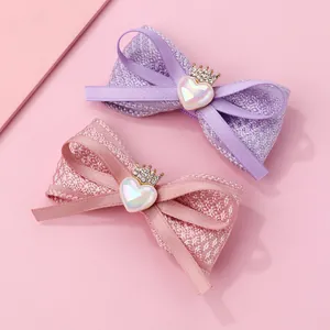 Détail de barrettes à nœuds en tissu avec cœurs brillants et couronnes pour filles