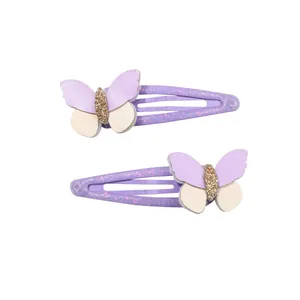 Dettaglio di due fermagli per capelli a farfalla con paillettes viola su sfondo bianco
