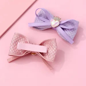 Détail de barrettes à nœuds rose et violet avec ornements cœur couronne et pinces