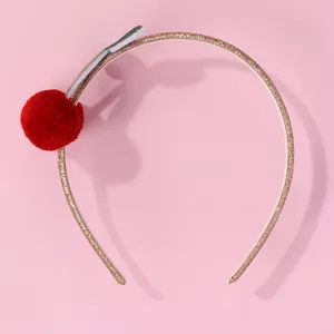 Dettaglio ravvicinato di un cerchietto glitterato dorato con pompon a forma di ciliegia