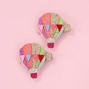 Close-up of glittery hot air balloon hair clips with colorful sequins and felt flags