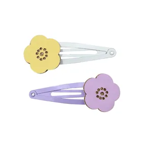 Detail of hollow floral hair clips in yellow and purple with glitter center on white background