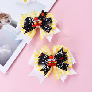 Détail de nœuds à cheveux pour l'école avec motif à carreaux jaunes et breloque livre