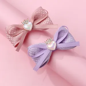 Détail de barrettes nœuds en tissu avec couronnes et perles de cœur pour filles