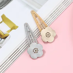 Close-up of glittery floral BB hair clips in champagne gold and silver leather