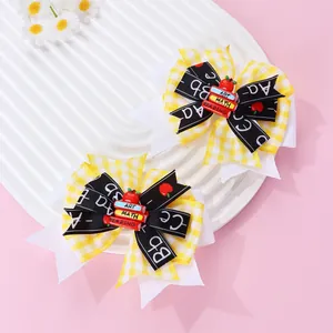 Détail de pinces à cheveux à nœuds scolaires avec motifs à carreaux et mini livres