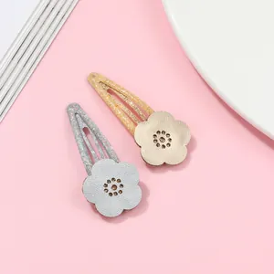 Detail of glitter floral BB hair clips in gold and silver with metallic petal textures