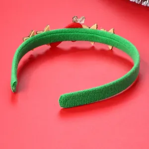 Dettaglio di un cerchietto natalizio in peluche verde con feltro rosso e stelle in legno