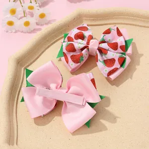 Detail of pink strawberry bow hair clips showing fabric texture and metal alligator clip