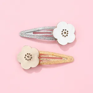 Detail of glitter flower BB hair clips with hollow laser-cut patterns on pink background