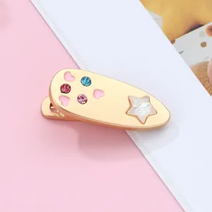 Detail of golden teardrop hair clip with colorful rhinestones and pink heart inlay