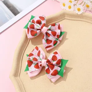 Detail of pink strawberry print fabric hair bows with layered green leaf accents