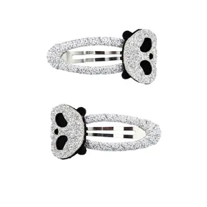 Detail of two panda-shaped hair clips with silver glitter finish and black ears