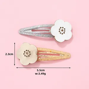 Detail view of two sequined flower hair clips with dimensions 5.5cm by 2.3cm