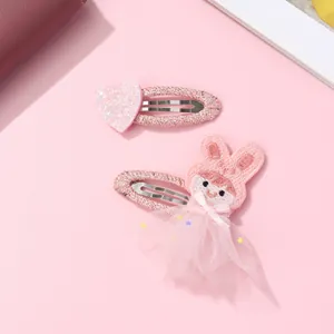 Détail de pinces à cheveux rose pailleté cœur et lapin avec jupe en tulle sur fond rose