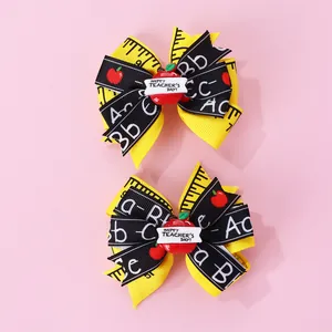 Détail de nœuds à cheveux thème enseignant avec ruban mètre jaune et petits charms pomme