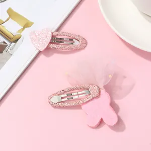 Détail macro des pinces à cheveux avec cœur pailleté rose et nœud en tulle pour fille