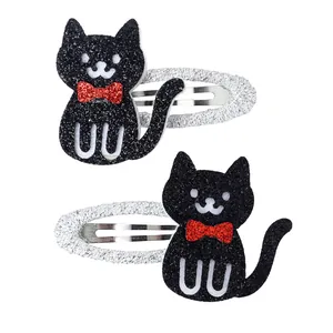 Detail of glittery black cat hair clips with red bows on silver textured snap pins