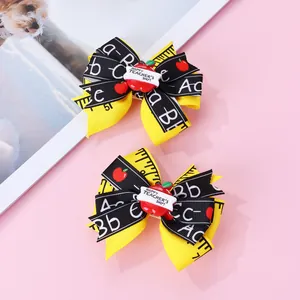 Détail de barrettes nœuds scolaires avec imprimé ABC, pommes et motifs de règle