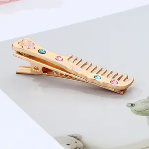 Detailed shot of golden comb hair clip with pink flower and sparkling rhinestones