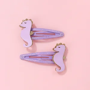 Gros plan d'une paire de barrettes hippocampe violettes à paillettes pour enfants