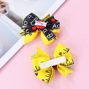 Détail de pinces à cheveux à nœud pour enseignant avec décor pomme et ruban règle