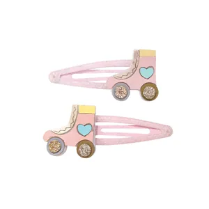 Detalle de pinzas para pelo de patines rosas con ruedas de purpurina y diseño de corazón