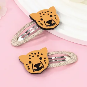 Détail de barrettes léopard avec patchs tête d'animal en cuir jaune et pinces en métal doré