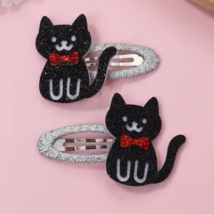 Close-up of black sequined cat hair clips with red bows and silver fabric wrapped base