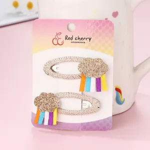 Detail of glitter cloud hair clip with long colorful rainbow ribbons on display card