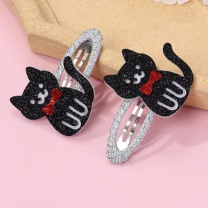 Close-up of glittery black cat hair clips with red bows and silver metal clips for girls
