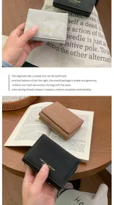 Portefeuille trois volets en velours bleu, marron et noir sur un fond en bois rustique