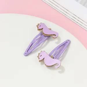 Gros plan de barrettes hippocampe violettes mignonnes avec paillettes dorées sur plat
