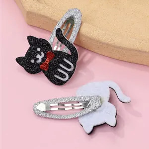 Detailed view of cartoon cat hair clips with black glitter, red bows and silver metal grips