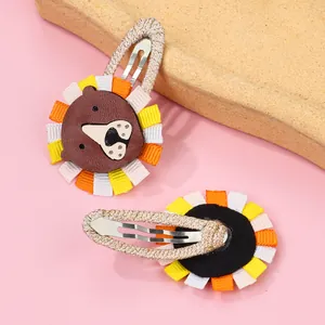 Detail of handmade lion pattern BB hair clips for girls with brown leather and ribbon