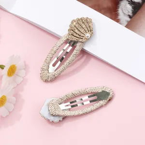 Detailed close-up of shell hair clips with glitter finish, pearls, and woven fabric wrap